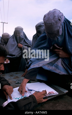 REBIRTH OF A NATION PUTTING THUMB PRINT AS SIGNATURE AS WOMEN COLLECT AID FROM CARE CHARITY ON OUTSKIRTS OF KABUL 2001 Stock Photo