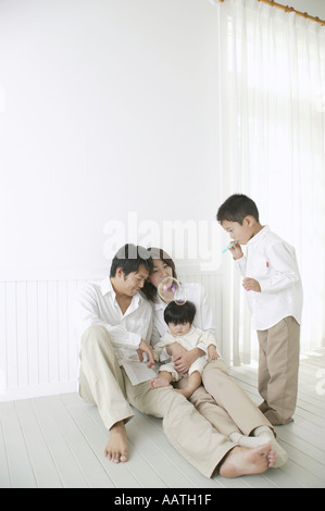 Son playing with bubbles and parents watching with smile. Stock Photo