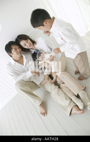 Son playing with bubbles and parents watching with smile. Stock Photo
