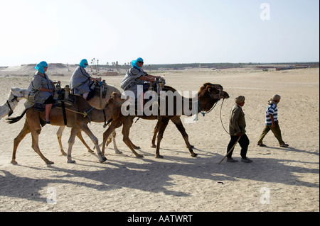 bedouin guides leading tourists out of the sahara desert at Douz Tunisia Stock Photo