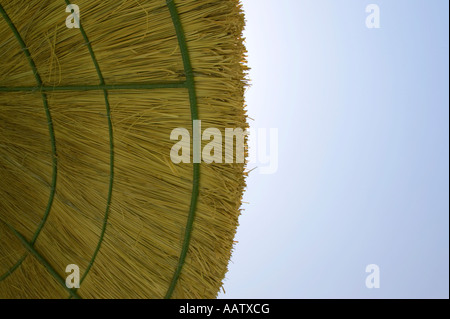 edge of straw parasol protecting against harmful UV rays from the sun blue sky Stock Photo