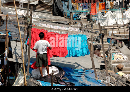 A dhobi wallah at Dhobi Ghat Mumbai (Bombay) hangs clothes to dry at the massive open air laundry. Stock Photo