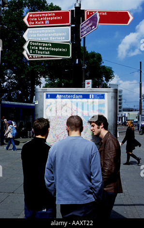 Young men looking at a street map sign near Central Station in Amsterdam Holland Stock Photo