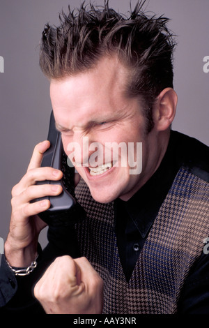 angry man on phone with hands clenched into a fist and snarling look on his face expressision vertical Stock Photo