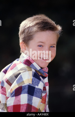 young 5 year old boy with smile on his face full of happiness in plaid western shirt close up vertical Stock Photo