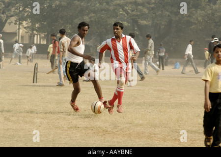 HMA78758 Indian boys playing football and cricket on playground Bombay Mumbai Maharashtra India Stock Photo