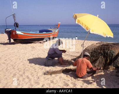 Algarve Albufeira 2 two fishermen sitting on beach working on fishing nets Stock Photo