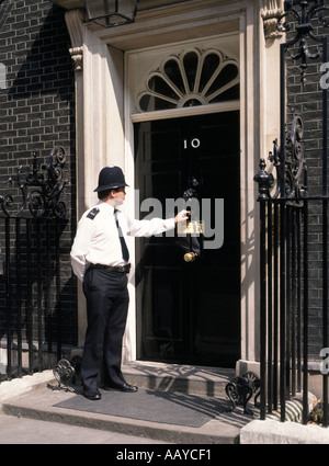 Number 10 ten Downing street front door and duty police officer knocking on door 'police knocking on door' Westminster London England UK Stock Photo