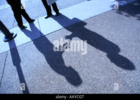 Businesspeople shaking hands with shadows on ground Stock Photo
