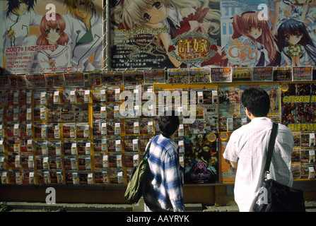 Otaku men looking at posters and vending boxes for toys in a street in Akihabara in Tokyo, Japan Stock Photo