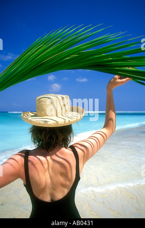 Woman in swimsuit holding palm frond leaf overhead for shade Lombok Island Indonesia Southeast Asia Model released image Stock Photo