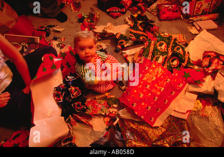 Overhead view of a young child sitting amidst the torn wrapping paper on the floor on Christmas morning Stock Photo