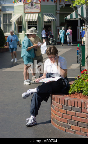 Woman talks on cell phone and studies map while planning day at Dollywood theme park in Pigeon Forge, Tennessee, USA Stock Photo