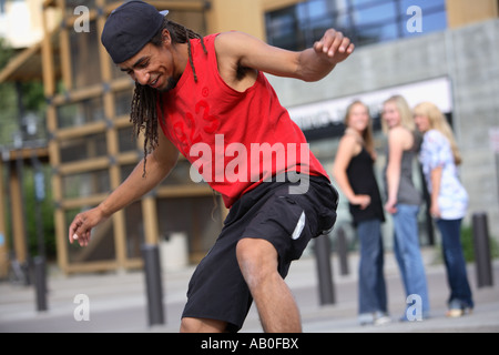 Skateboarder doing a trick with girls watching Stock Photo