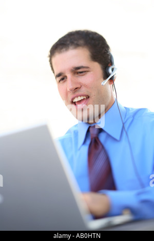 Young businessman working on laptop with headset on Stock Photo