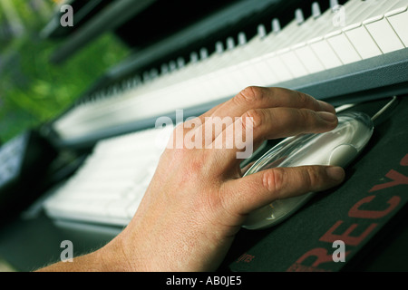 Recording music in recording studio to hard disc - close up of hand operating mouse next to computer and musical keyboard Stock Photo