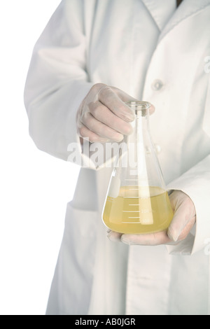 Person in lab coat holds beaker of liquid Stock Photo