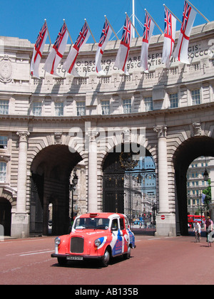 London Taxi coloured in the Union Jack flag with white ensign flags flying above on the Admiralty Arch, The Mall, London, England, United Kingdom Stock Photo