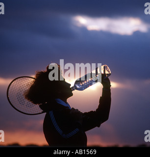 woman tennis player drinking water at sunset Stock Photo