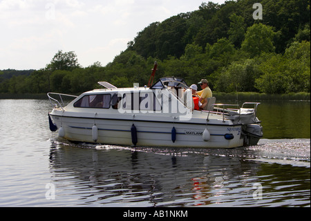 side on view of family piloting tourist cabin cruiser cruising along lower lough erne Stock Photo