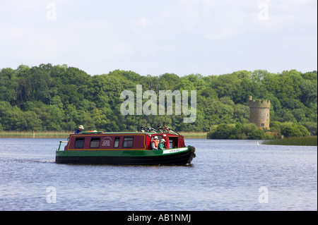 tourist steering narrowboat barge past Crichton Tower on Gad Island part of the Crom Castle estate lower lough erne Stock Photo