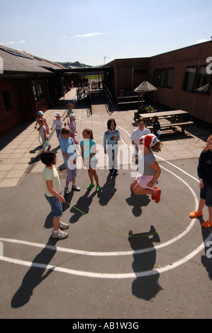 Ysgol Gymraeg Aberystwyth welsh language primary school pupils playing skipping rope game in sunshine at break time Wales UK Stock Photo