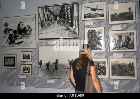 Woman studies Vietnam War photographs in gallery War Remnants Museum Ho Chi Minh City Vietnam Stock Photo