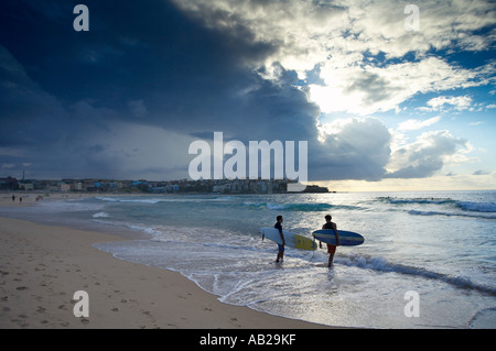 two surfers entering the water on Bondi Beach early morning Sydney New South Wales Australia Stock Photo