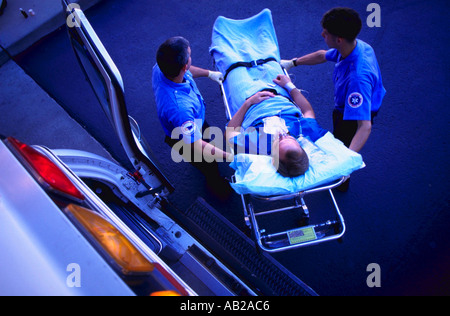 Overhead view of two emergency medical technicians taking patient on gurney out of ambulance Stock Photo