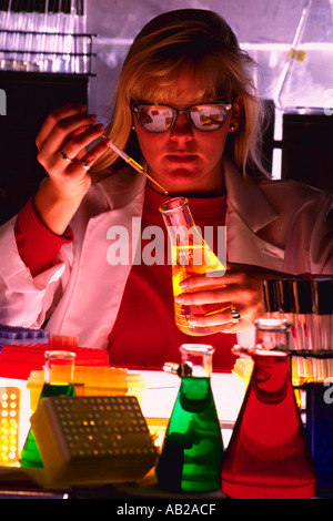 Female chemist with red yellow and green liquid in beakers Stock Photo