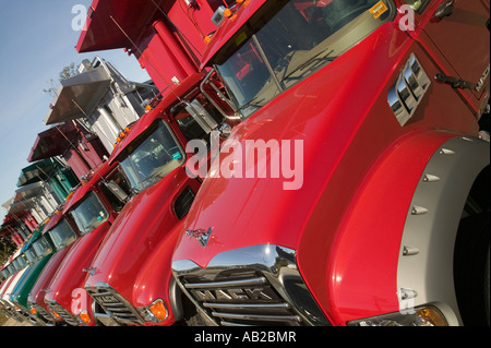 Bright red Mack dump trucks line the road in a row in Maine near the New Hampshire border Stock Photo