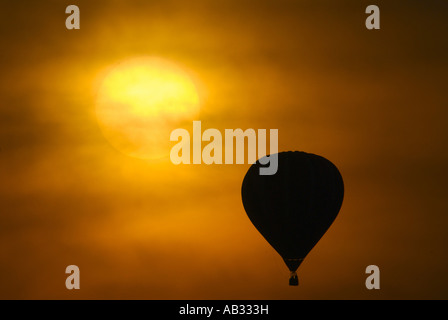 Hot air balloon flying near the sun in a red sky as the sun sets in dusty conditions. From the archives of Press Portrait Service Stock Photo