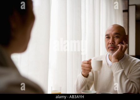 Senior man drinking coffee senior woman in foreground Stock Photo