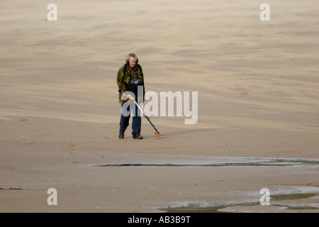 MAN USING A METAL DETECTOR ON A SANDY BEACH Stock Photo