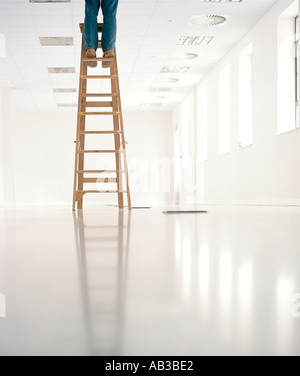 man standing on top of ladder in empty office Stock Photo