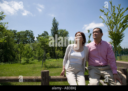 Mature couple sitting on fence Stock Photo
