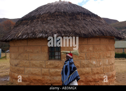 A woman passes a traditional basotho hut in Lesotho, Africa Stock Photo