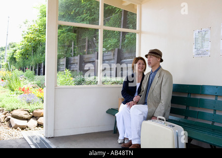 Senior couple sitting on bench at station Stock Photo