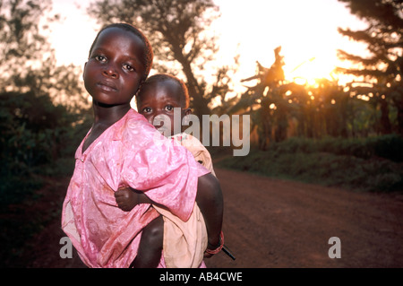 Sad looking young teenage local girl carrying a baby on her back. Stock Photo