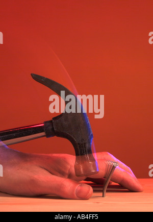 hammer glancing off nail and hitting thumb Stock Photo