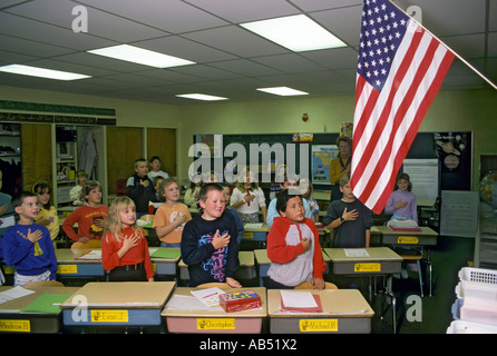 Third grade elementary school class recites the pledge of allegiance to the American flag every morning before beginning studies Stock Photo