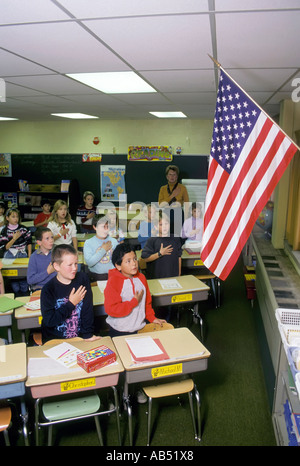 Third grade elementary school class recites the pledge of allegiance to the American flag every morning before beginning studies Stock Photo