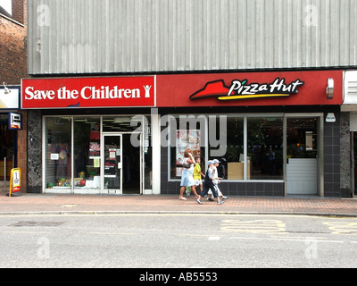 High Street Brentwood Essex Save the Children Charity Shop located next to a Pizza Hut fast food restaurant people passing Stock Photo