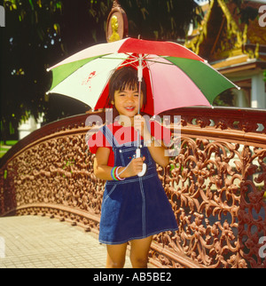 Single small Thai girl holding an umbrella to protect her against the sun in Bangkok Thailand Stock Photo