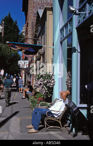 Man relaxing on bench in sunshine in front of shop on Water Street Port Townsend Washington Stock Photo