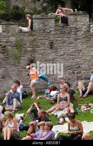 Fans sat on wall and grass listening to a band in Bishops Garden during the annual Brecon Jazz Festival Powys Wales UK Stock Photo