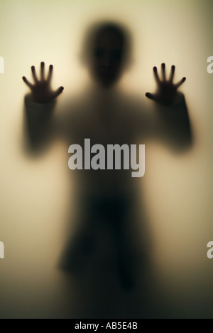 Boy 7, 8, 9, 10, 11, 12, 13, 14 years old  Figure behind transparent wall Stock Photo