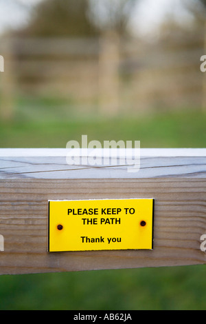 Yellow Sign on Fence - Please Keep to the Path Stock Photo