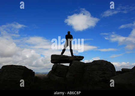 A walker stands on Alcomden Stones above Haworth in the South Pennines Stock Photo