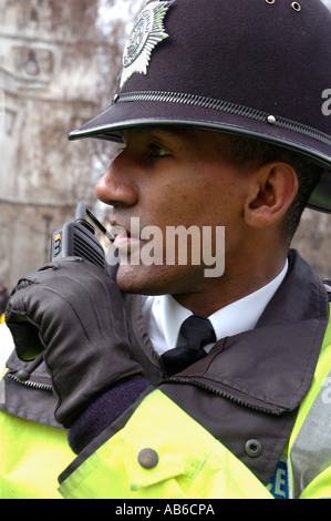 Black police officer talking on short band radio whilst on duty in Central London. Stock Photo